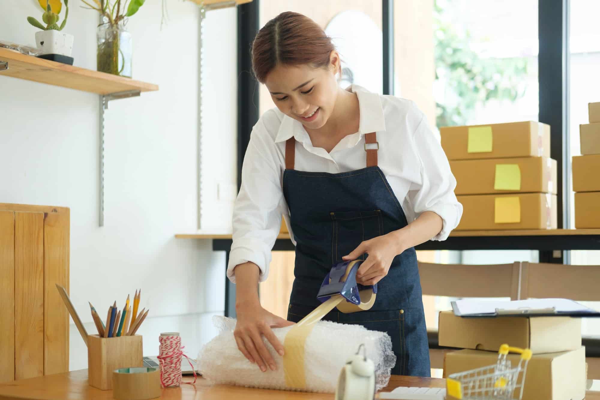 Female online business owner packing order box for dispatching.