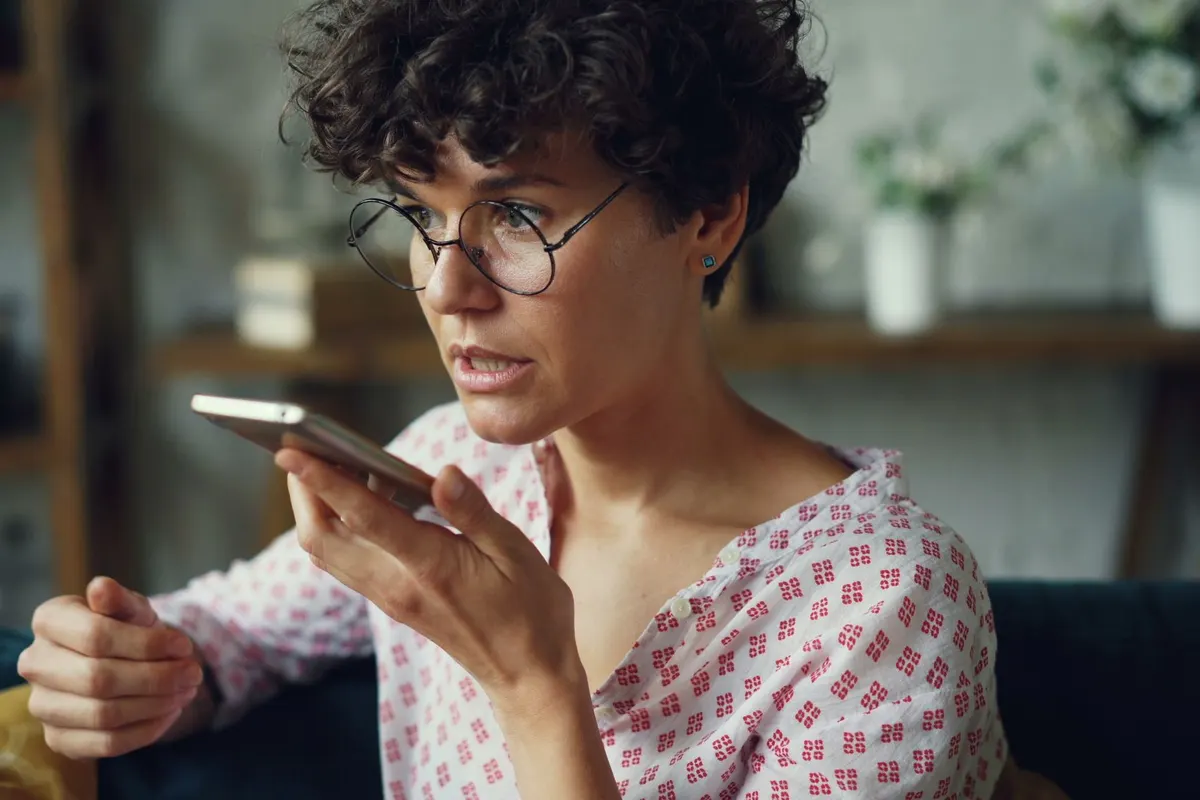 A woman at home asking her phone a question out loud